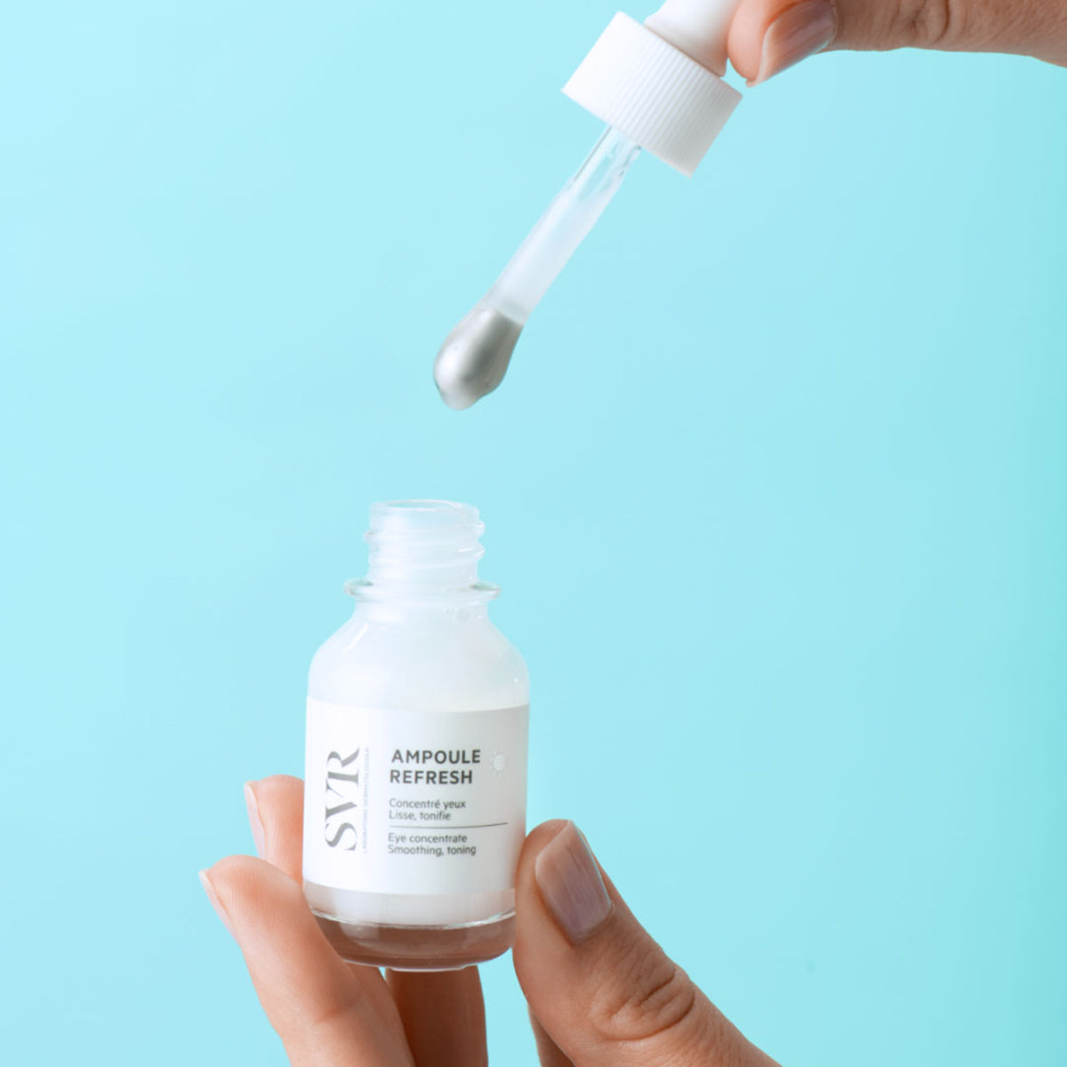 SVR Ampoule Refresh eye concentrate in a small glass bottle with a silver-tipped dropper against a light blue background.