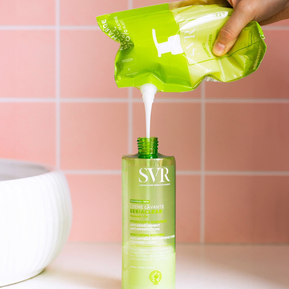 Refilling a green 400ml SVR Sebiaclear Creme Lavante bottle from a matching eco-friendly plastic pouch.