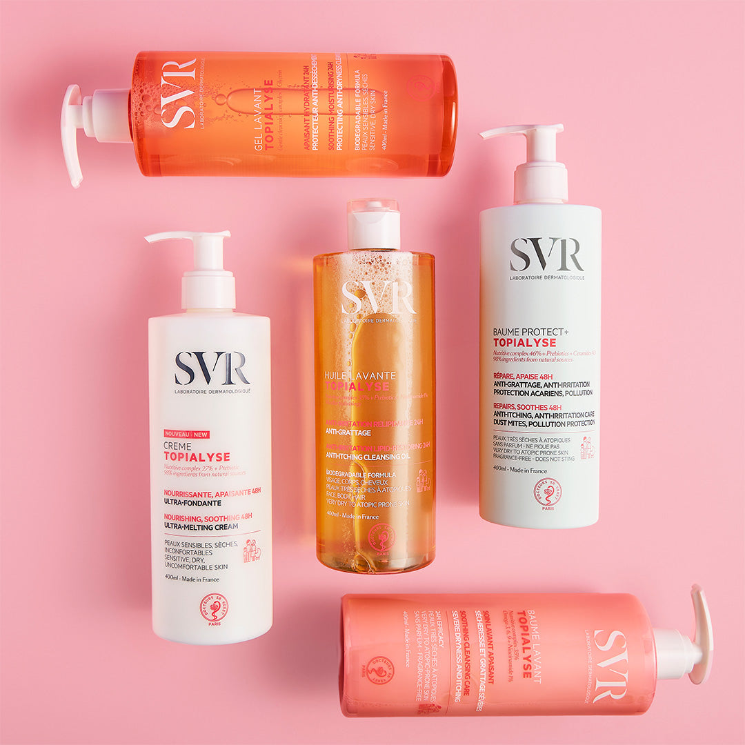 Five SVR TOPIALYSE skincare bottles with pump dispensers arranged on a soft pink background.