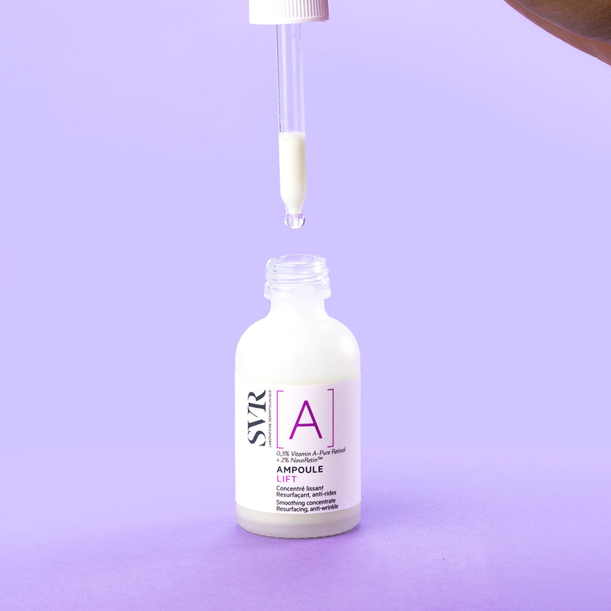 SVR Ampoule Lift serum bottle with a glass dropper dispensing a drop of white anti-wrinkle concentrate on a purple background.