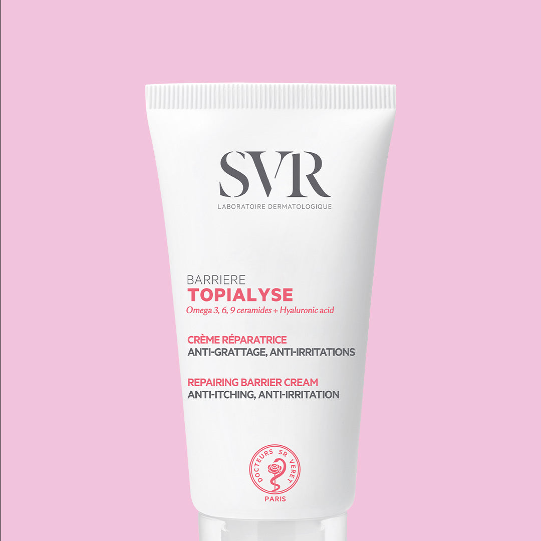 White SVR TOPIALYSE Barrière repair cream tube with pink text and branding on a soft pink background.