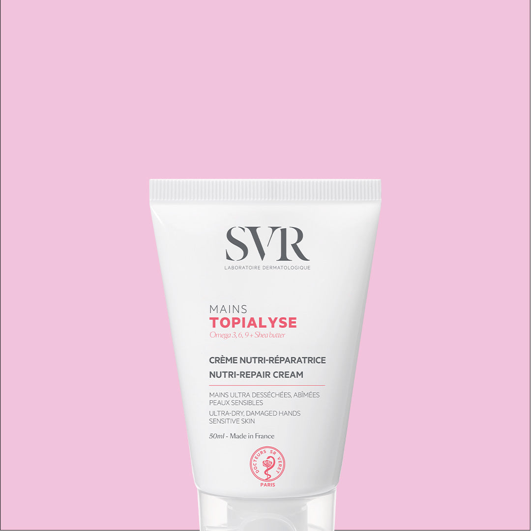 SVR TOPIALYSE Mains 50ml nutri-repair hand cream in a white squeeze tube against a soft pink background.