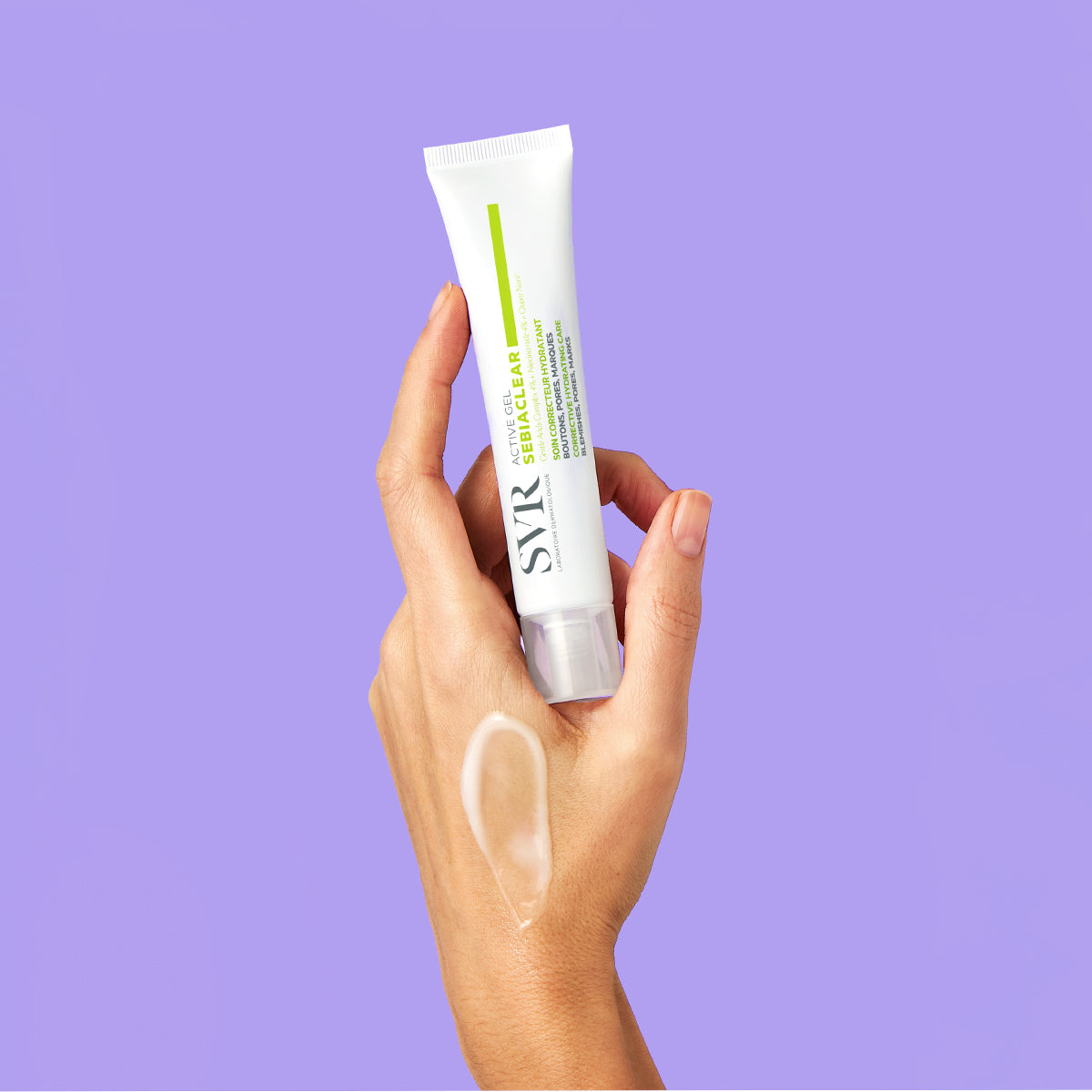 Hand holding a white SVR Sebiaclear Active Gel tube with a clear gel swatch on skin against a purple background.