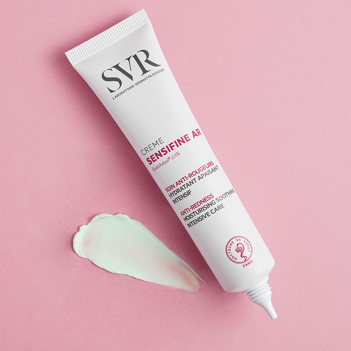 SVR Sensifine AR anti-redness cream tube with a light green product swatch on a soft pink background.