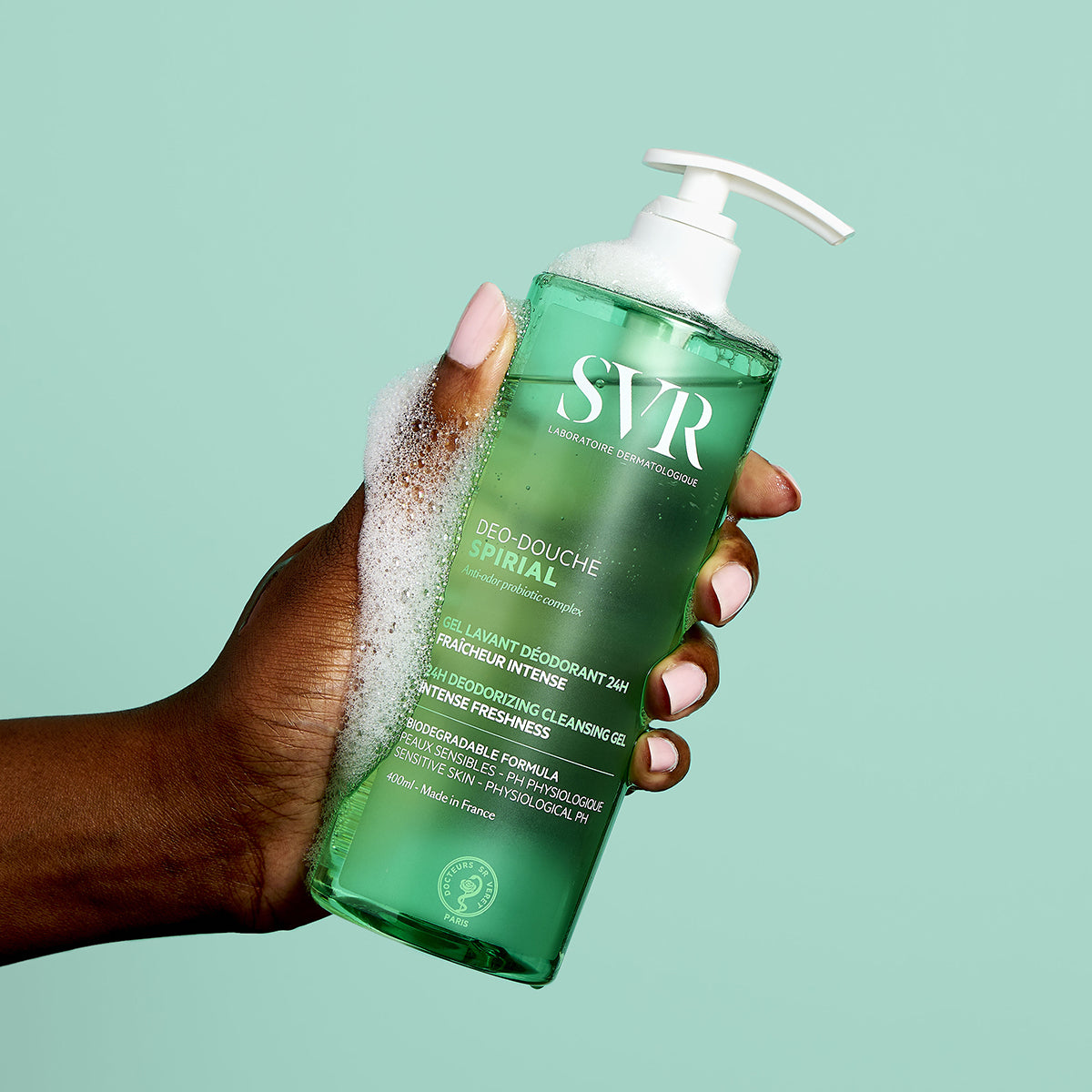 Hand holding a 400ml bottle of SVR Spirial Deo Douche cleansing gel with white pump dispenser and soapy lather.