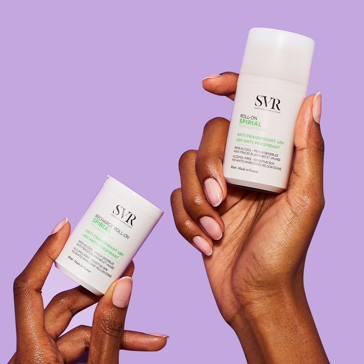 Hands holding SVR Spirial 48h anti-perspirant roll-on and refill bottles against a purple background.