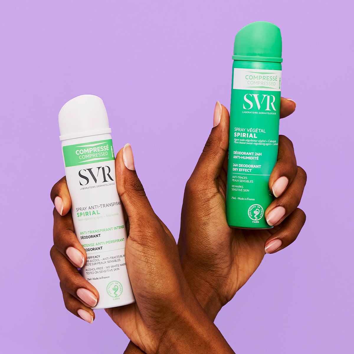 Hands holding white and green SVR Spirial compressed deodorant spray bottles against a purple background.