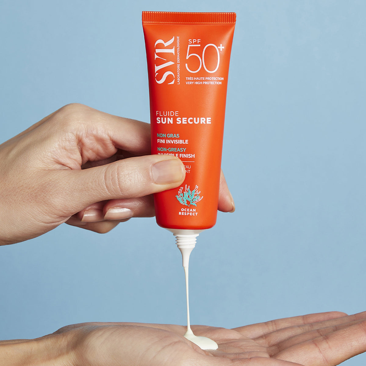 Hand squeezing a bright orange SVR SUN SECURE SPF50+ sunscreen tube, dispensing white fluid onto an open palm.
