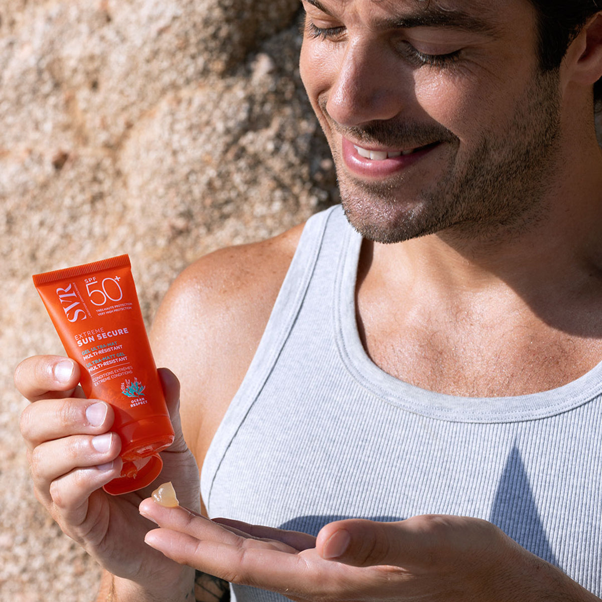 Man holding an orange SVR SUN SECURE Extrême SPF50+ gel tube and applying the clear product to his palm.