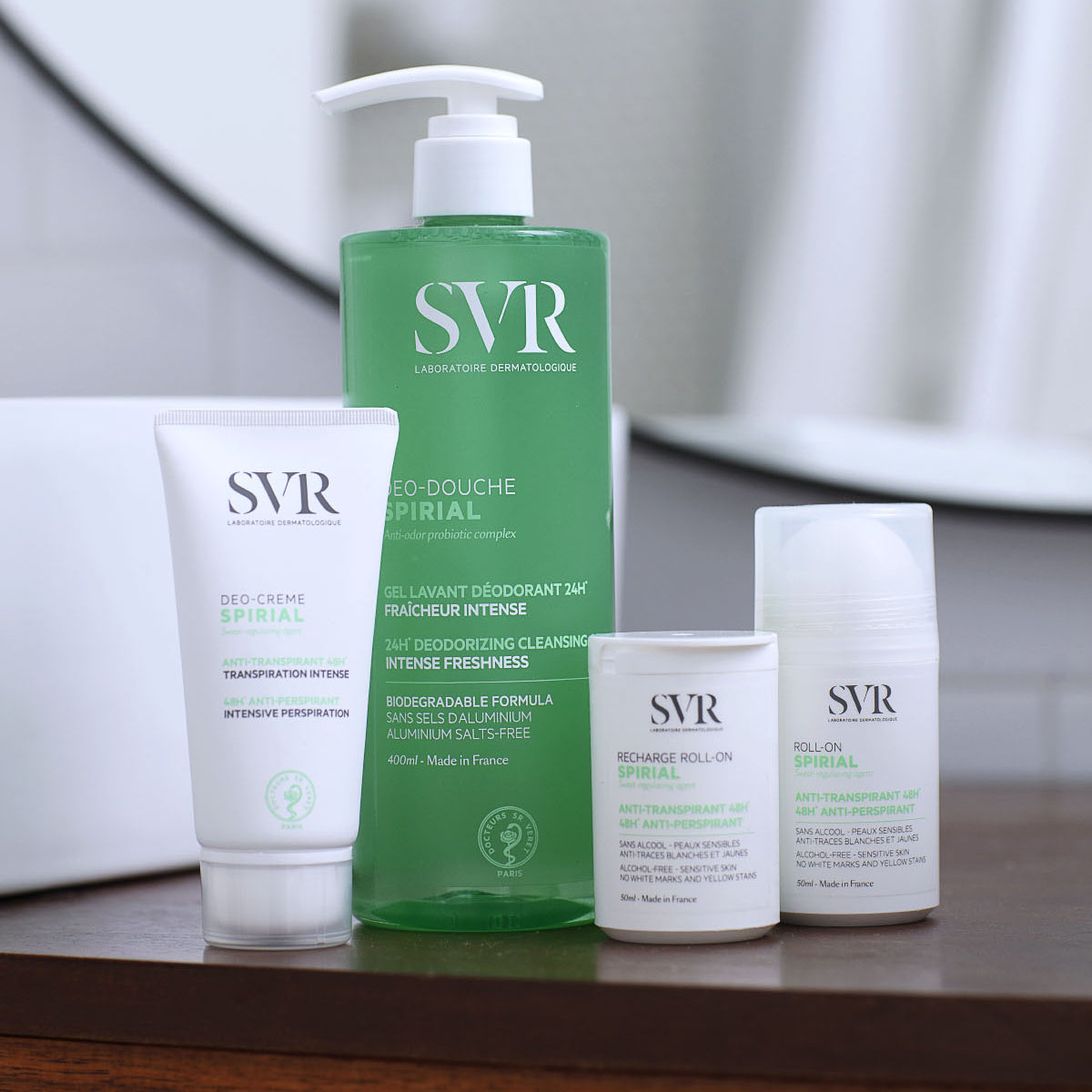 SVR Spirial deodorant range including a white cream tube, green pump bottle, and two roll-on antiperspirants on a shelf.