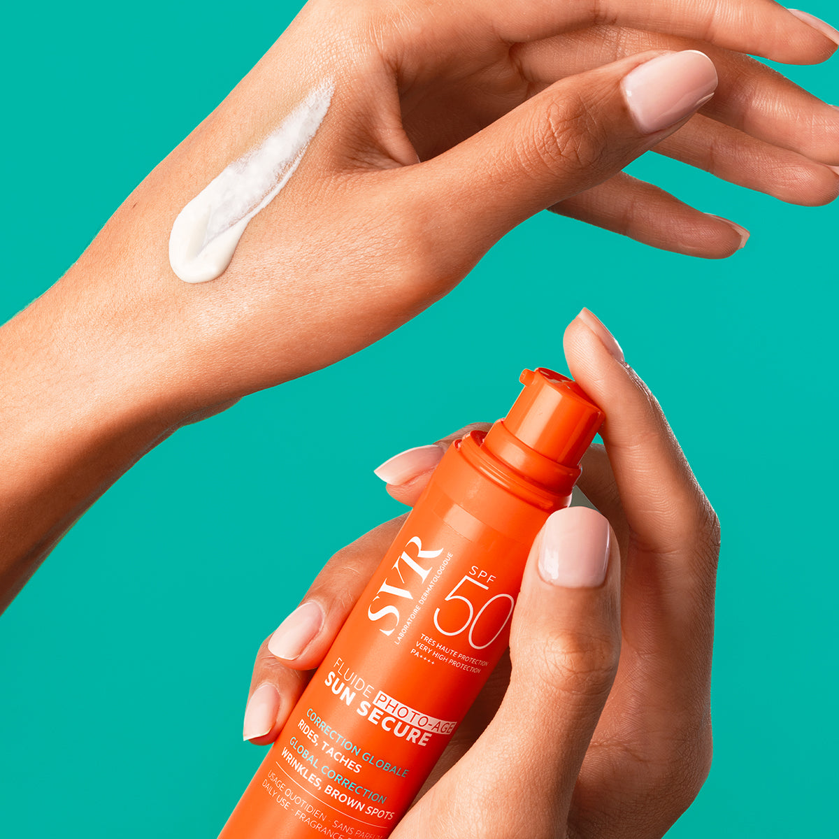 Hands holding an orange SVR SUN SECURE SPF50+ pump bottle with a white cream swatch applied to the skin.